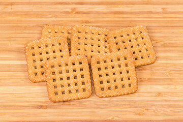 Flat crunchy square-shaped sugar shortbread cookies on wooden surface