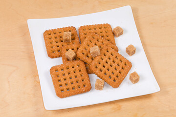 Flat crunchy square sugar shortbread cookies and brown sugar cubes