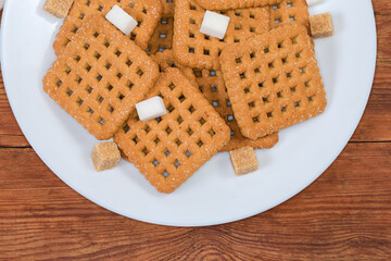 Flat square sugar cookies, sugar cubes on dish, top view
