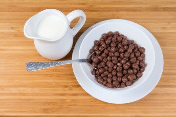 Breakfast cereal chocolate balls in bowl, milk in milk jug