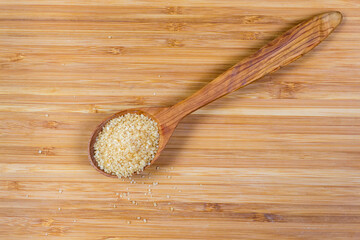 Brown sugar in wooden spoon on wooden board, top view
