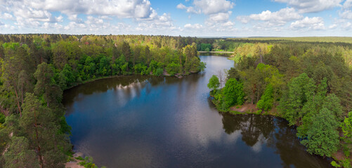 Lake with coniferous and deciduous forest on shores, aerial view