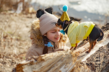 Outdoor portrait of 10- 11 year old girl. A girl with a chihuahua dog. Pet in clothes. birthday