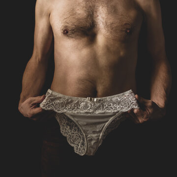 Unrecognizable young man trying on female lace panties