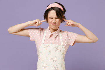 Young housewife housekeeper chef cook baker woman wear pink apron cover ears with hands fingers do not want to listen scream isolated on pastel violet background studio portrait. Cooking food concept