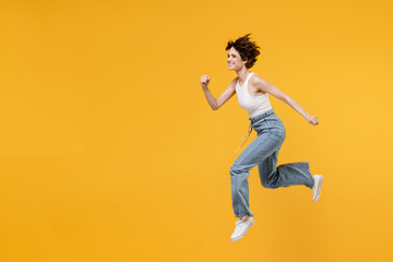 Fototapeta na wymiar Full length side view young sporty caucasian happy woman 20s with bob haircut wearing white tank top shirt jumping high run fast isolated on yellow background studio portrait People lifestyle concept