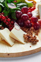 Different varieties of cheese with walnuts and grapes.