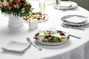 Vitello tonnato, on a table with white tablecloths, banquet table. Dish with marinated veal with creamy tuna sauce and bread on a wooden background.