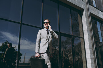 Bottom view young successful employee business man 20s wear grey suit walking go near office glass...