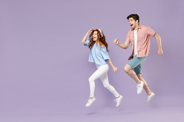 Full length side view traveler tourist woman man couple in shirt hurrying up run fast jump high isolated on purple background. Passenger travel abroad on weekends getaway. Air flight journey concept.