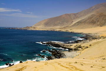Rough harsh coastal scenery: View on uninhabited barren bay with empty sand beach at endless pacific coast with dry arid mountains - Pan de Azucar, Chile