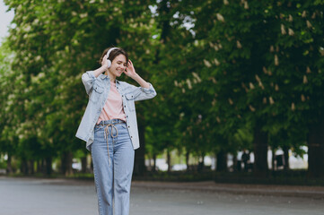 Young satisfied happy student stylish caucasian woman 20s wearing jeans clothes headphones listen...