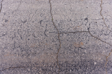 Obraz premium The texture of the asphalt in the cracks, hard crumbling asphalt in the village.