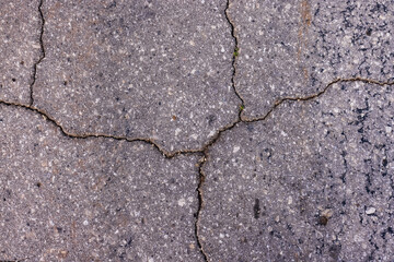The texture of the asphalt in the cracks, hard crumbling asphalt in the village.