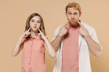 Young parent man have fun with child teen girl in casual clothes. Daddy look at little kid daughter pointing index fingers on blowing puffing cheeks with funny face mouth isolated on beige background - obrazy, fototapety, plakaty