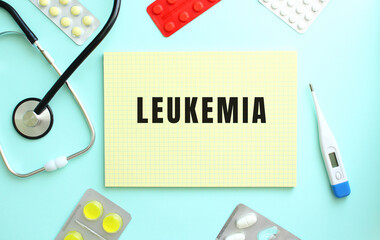 The text LEUKEMIA is written in a yellow notebook that lies next to the stethoscope, medicine on a...