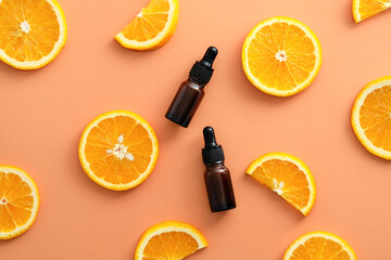 Vitamin C brown amber glass dropper bottles and sliced orange top view. Natural cosmetics branding.