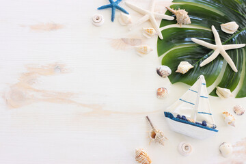 nautical concept with white decorative sail boat, seashells over wooden background