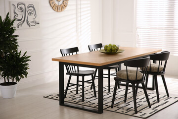 Stylish wooden dining table and chairs in room. Interior design
