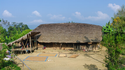 Landscape view of traditional Naga Konyak tribe house with typical curved roof and crops drying in...