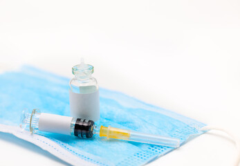 Syringe  and Vaccine bottle with blank labels on blue protective mask. Healthcare and Medicine...