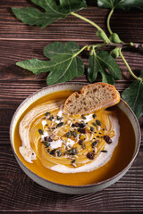Food photography of a vegan cream soups on a table of old wood. Vegetables recipe of a creamy soup. Puree of seasonal products on a wooden board among fig leaves