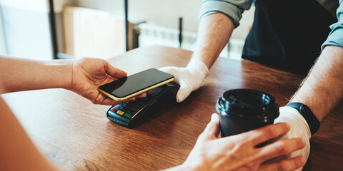 Mobile and safety wireless payment using cell phone and bank terminal. Coffee small business, close-up