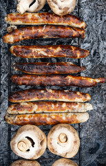 Bbq sausages on the coals grill. Grilled Bratwurst and mushrooms.