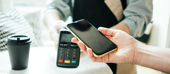 Mobile and safety wireless payment using cell phone and bank terminal. Coffee small business, close-up