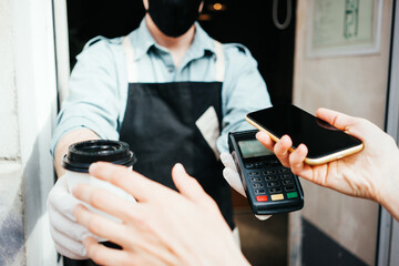 Mobile and safety wireless payment using cell phone and bank terminal. Coffee small business, close-up