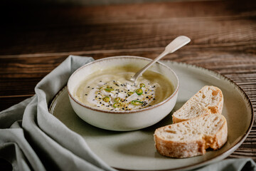Food photography of a vegan pumpkin cream soup and bread with selective focus. Vegetables recipe. An autumn puree of seasonal products on a wooden table with vintage look.