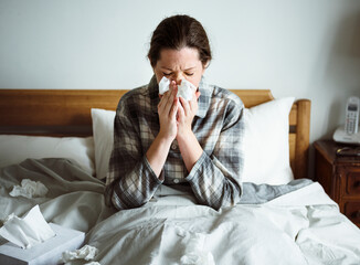 A woman suffering from flu in bed - obrazy, fototapety, plakaty