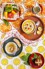Flat lay photography of a vegan pumpkin cream soup and bread. Vegetables recipe.  Top view of an puree of seasonal products with spices and retro pattern fabric tablecloth.