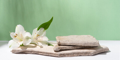 Background for cosmetic products of natural green color. Stone podium with white flowers. Front view.