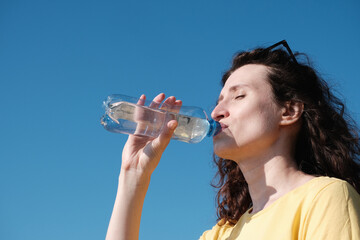 Girl drinks water from a bottle in hot weather.