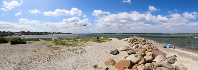 Panorama of kite surfing activity at the Baltic Sea beach of Laboe in Germany on a sunny day.