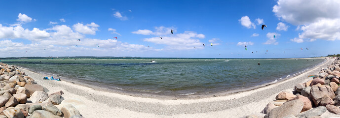 Panorama of kite surfing activity at the Baltic Sea beach of Laboe in Germany on a sunny day.