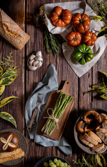 Flat lay dark photography of asparagus, bread, tomatoes,garlic and plums on a table of old wood. Vegetables recipe of for autumn or winter. Moody top view of seasonal products on a wooden table.