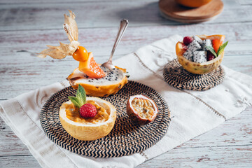 Bright food photography of mix of sliced tropical fruits. Backdrop with a tray with passion fruit,...