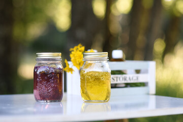 Natural cosmetic jars with flowers and essential oils macerating in the forest