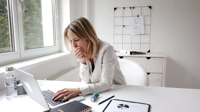 Coughing businesswoman using inhalator in home office