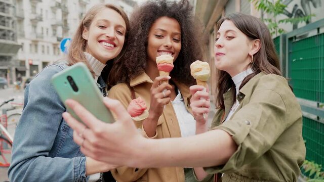 Girlfriends taking selfie in the street, eating ice cream