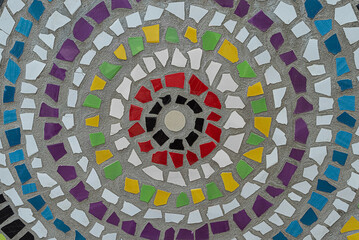 Weathered mosaic in circle shape from broken ceramic tiles on wall