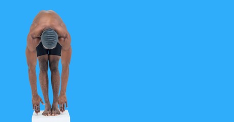 Composition of male swimmer on starting block with copy space isolated on blue background