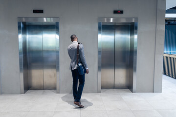 Rear view of african american businessman waiting for the lift at modern office