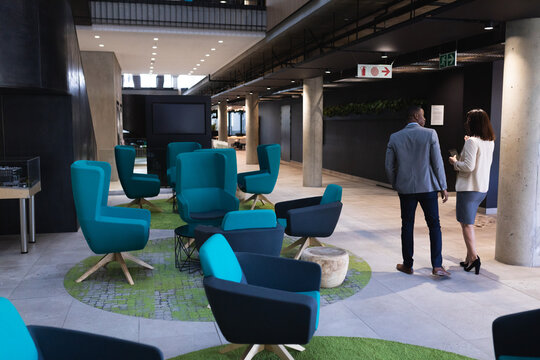 Diverse businessman and businesswoman discussing over digital tablet at modern office