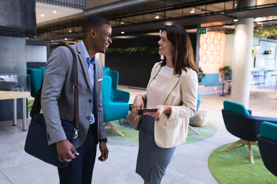 Diverse Businessman And Businesswoman Smiling While Discussing Over Digital Tablet At Office