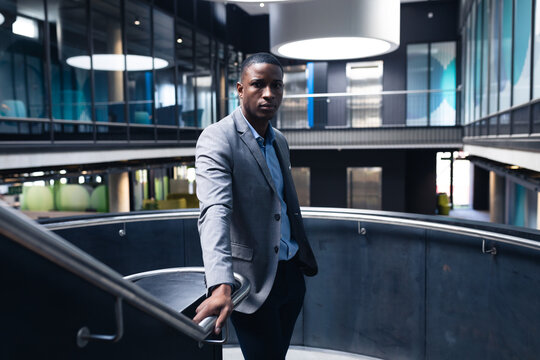 Portrait of african american businessman standing on the stairs at modern office