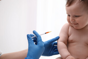 Doctor vaccinating baby against light background. Health care