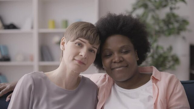 Multiethnic lesbian couple leaning heads together, same-sex love relationship